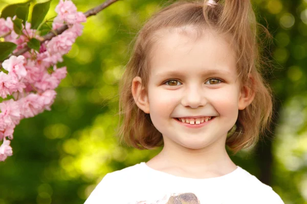 Ritratto di bambina felice vicino al ciliegio giapponese — Foto Stock