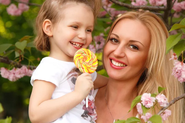 Moeder met kleine dochter likt snoep voorjaar park buiten — Stockfoto