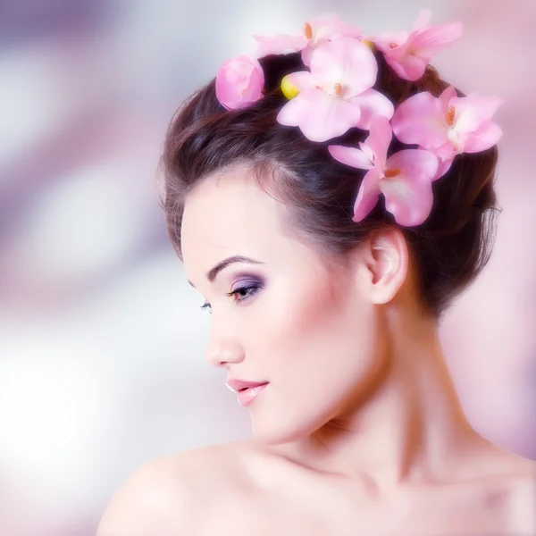 Hermosa chica adolescente sonriendo y con orquídea de flores — Foto de Stock