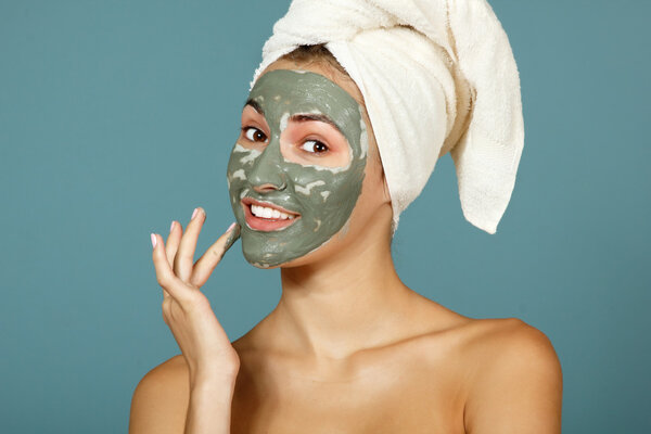 Teen girl applying facial clay mask