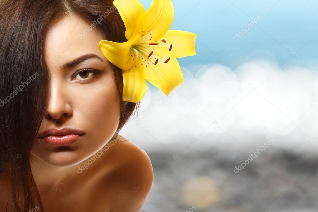 Woman with yellow flower lily in her hair