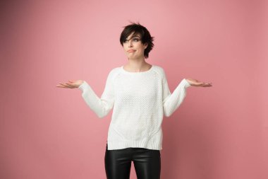 Hiçbir şey yapmayan güzel bir genç kadın ve yüz ifadeleri özür dilemek için beden dilini kullanıyor, pişmanlık, başarısızlık, çaresizlik, pembe arka plan üzerine stüdyo çekimi.. 