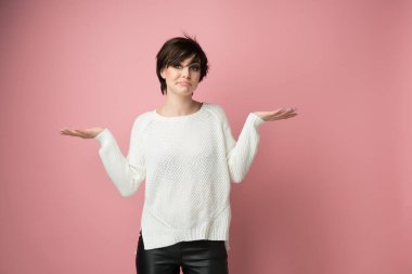 Hiçbir şey yapmayan güzel bir genç kadın ve yüz ifadeleri özür dilemek için beden dilini kullanıyor, pişmanlık, başarısızlık, çaresizlik, pembe arka plan üzerine stüdyo çekimi.. 