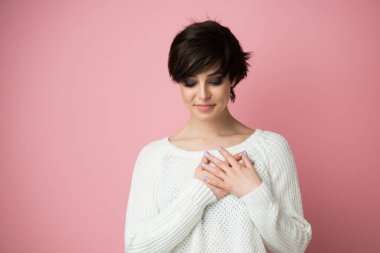 Göğsünde ellerle gülümseyen, yüzünde minnet ifadesi olan, başarıya inanan, hayallerinin gerçekleşmesini isteyen genç, güzel bir kadın, geleceği görselleştirir..