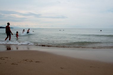 Günbatımında Sicilya 'da (İtalya) sakin Akdeniz' de yüzen insanlar