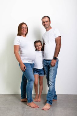Hamile anne, baba ve kız evde poz veriyor. Hamilelik. 