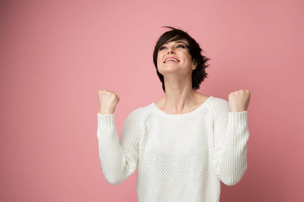 Beautiful young woman happy and excited expressing winning gesture. Successful and celebrating victory, triumphant, studio shot over pink background