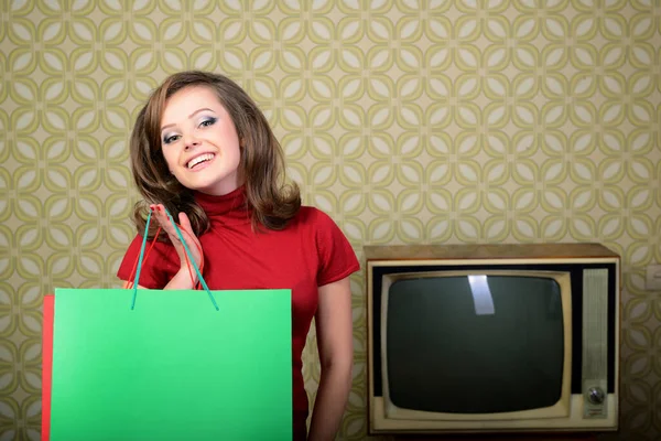 年轻迷人的女人拿着购物袋 房间里有复古墙纸和复古电视机 复古风格60 70年代 — 图库照片