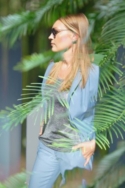 Açık mavi takım elbise ve çam dalları giyen güzel bir moda kadını, çifte teşhircilik, modern sanat. Posterler, kapaklar ve web için ideal tasarım ögesi