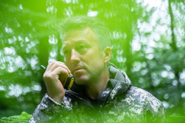 Olgun adam ormanda telsizle konuşur. Açık havada erkek portresi. 