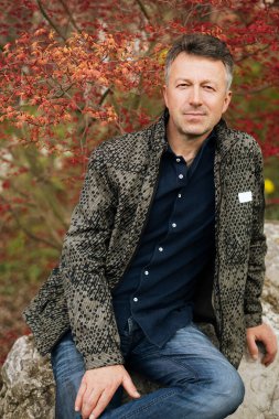 Bahar parkında poz veren yakışıklı olgun bir adamın portresi.