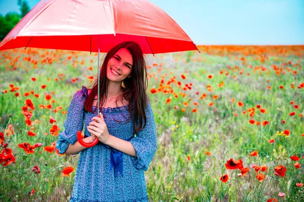 年轻美丽的微笑的女人 戴着夏天的雨伞 拿着红色的雨伞 在罂粟地里 迷人的女孩在雨前散步 大自然在室外 — 图库照片