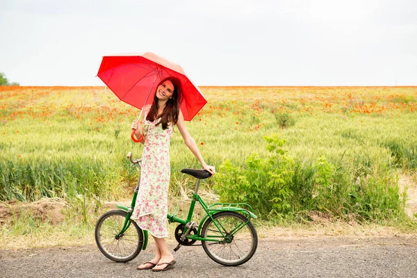若い自転車の美しい女性は ケシ畑 夏の屋外を歩いています 魅力的な女の子保持赤傘とともにレトロバイク — ストック写真