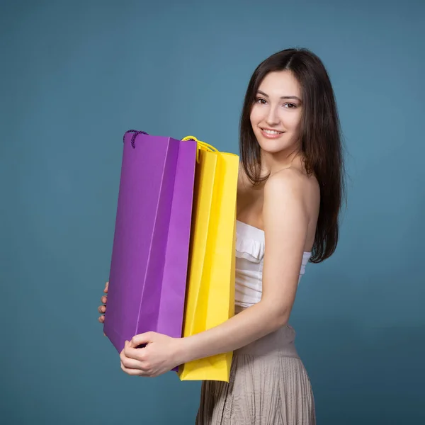 快乐的年轻女性购物狂 带着购物袋 与蓝色背景隔离 — 图库照片