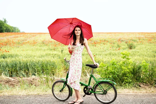 若い自転車の美しい女性は ケシ畑 夏の屋外を歩いています 魅力的な女の子保持赤傘とともにレトロバイク — ストック写真