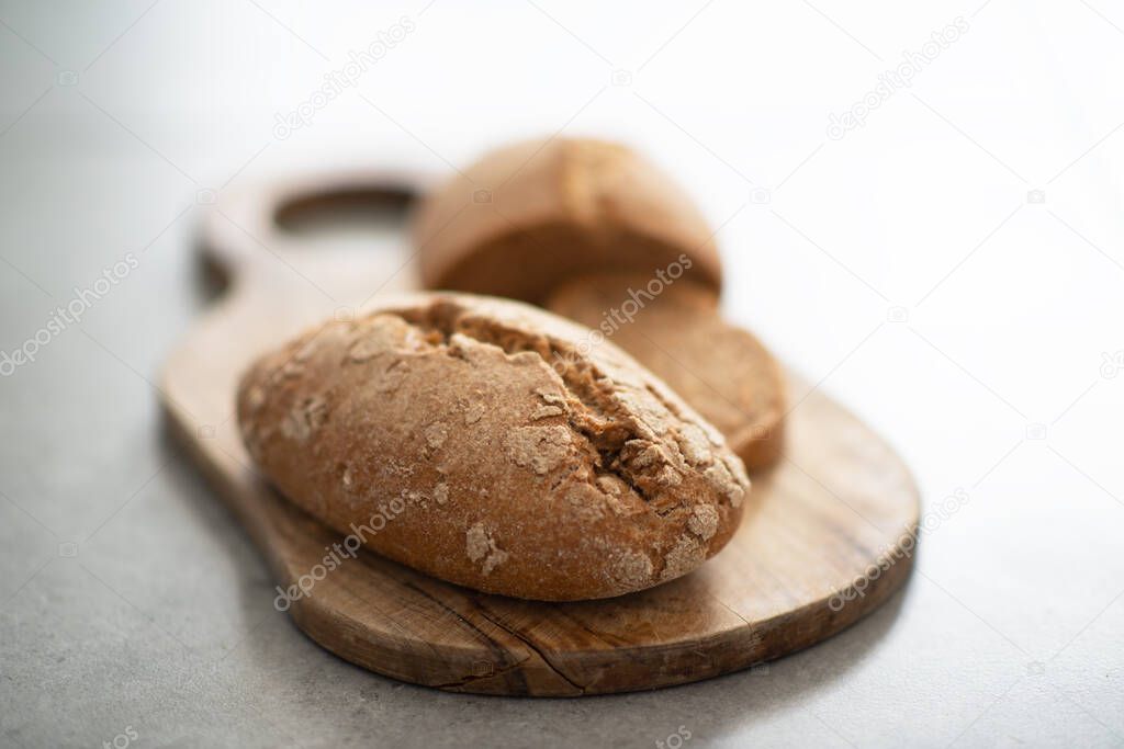 Homebaked hot appetizing bread with crispy crust sliced on wooden cutting board