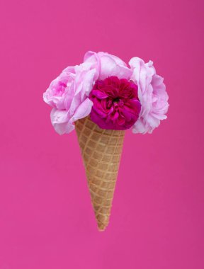 Dondurmalı waffle külahı ve pembe arka planda bir buket yaz çiçeği gülü. Diyet ve düşünme kutu tasarımı konsepti dışında