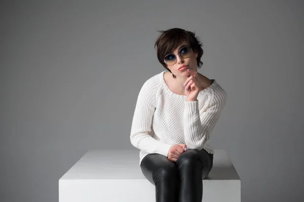 Mujer Joven Emocionada Con Gafas Sol Sentado Cubo Blanco Estudio — Foto de Stock