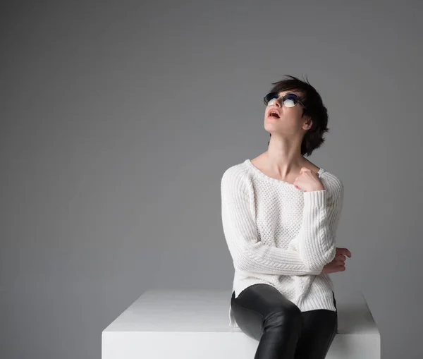 Excited Young Woman Sunglasses Sitting White Cube Studio Isolated Gray — Stock Photo, Image