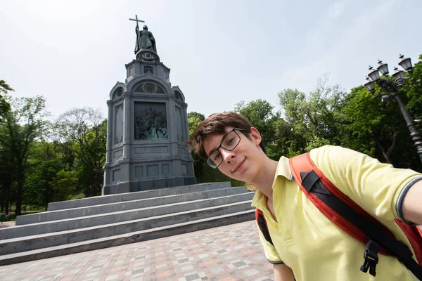 若いですハンサムな15歳の男の子カメラを見て 幸せな笑顔は 記念碑の上にスマートフォンで自撮りを取りますウラジミール キエフの夏の街の中心部 ヨーロッパ — ストック写真