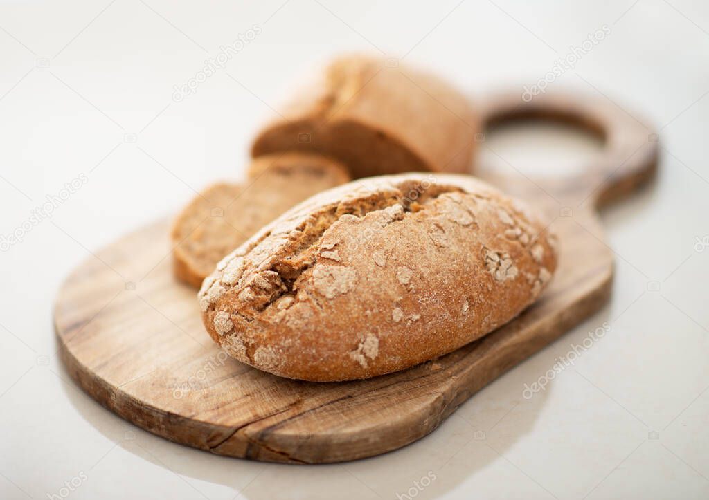 Homebaked hot appetizing bread with crispy crust sliced on wooden cutting board