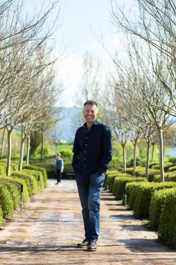 Bahar bahçesinde poz veren yakışıklı olgun bir adamın portresi.