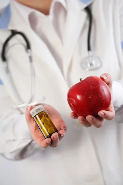 Apfel gegen Drogen in der Hand des Arztes. — Stockfoto