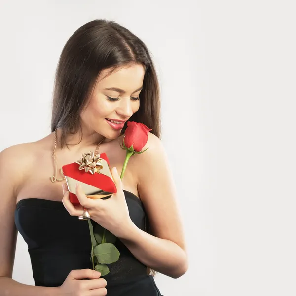 Young woman holding a gift and a flower — Stock Photo, Image