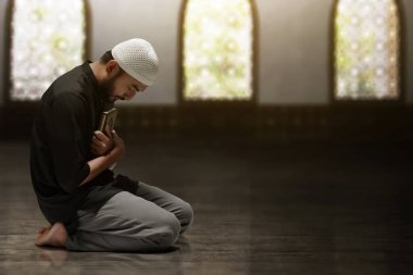 Kutsal Kuran 'ı tutan dindar Asyalı Müslüman adam.