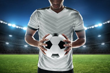Futbol oyuncusu stadyumda top tutuyor.