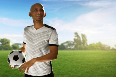 Futbolcu sahada topu tutuyor.