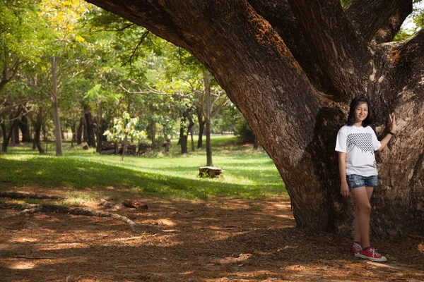 Jeune femme debout sous un grand arbre . — Photo