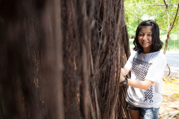 Young woman standing under a large tree. Stock Picture