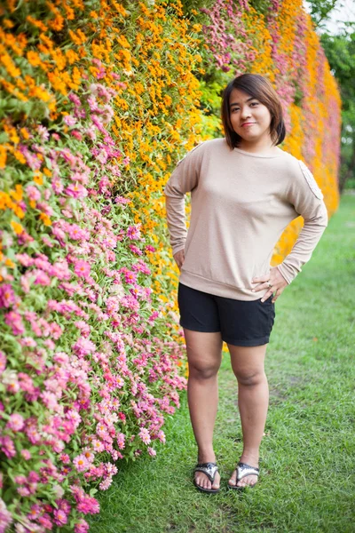 Portrait Asian woman standing near yellow flowers. — Stock Photo, Image