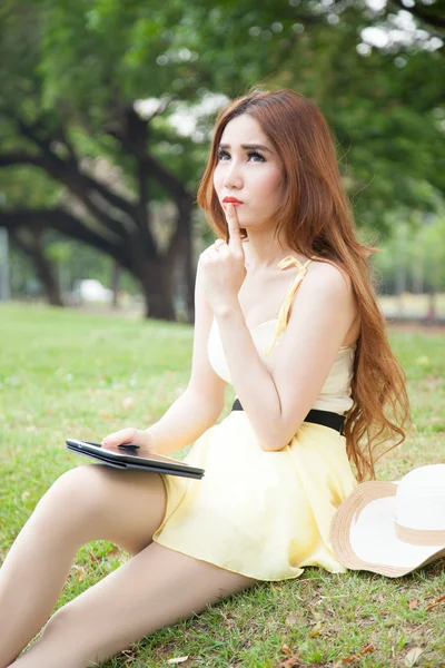 Aziatische vrouw zitten in het park en denken. — Stockfoto