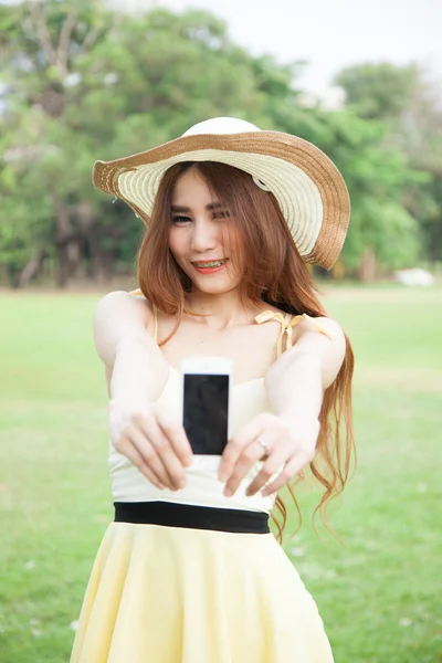 Азиатка улыбается и вручает мобильный телефон . — стоковое фото