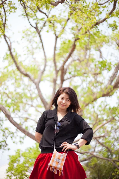 Asiatische Frauen schwarzes Hemd steht unter einem Baum. — Stockfoto