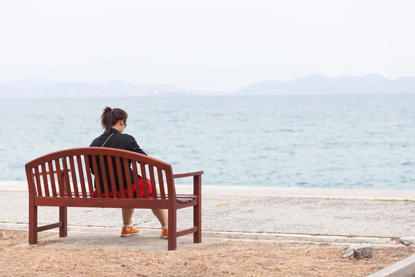 Aziatische vrouwen zwart shirt. zittend op houten bench. — Stockfoto