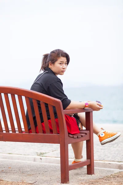 Asiatische Frauen schwarzes Hemd. auf Holzbank sitzend. — Stockfoto