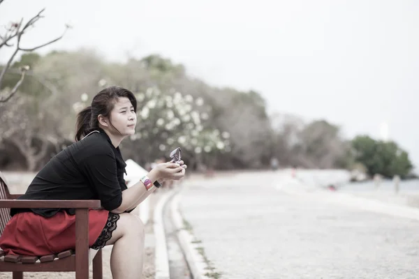 Femmes asiatiques chemise noire. Assis sur un banc en bois . — Photo