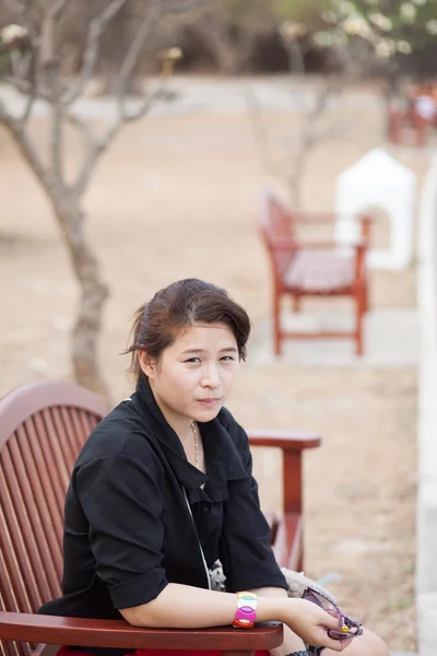 Asiatische Frauen schwarzes Hemd. auf Holzbank sitzend. — Stockfoto