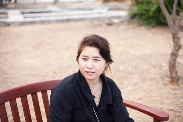 Asian women black shirt. Sitting on wooden bench. Royalty Free Stock Images