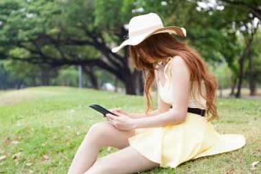 çimenlerin üzerinde oturan ve bir tablet kullanarak kadın.