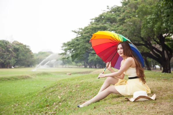 Женщина с зонтиком и сидящая на газоне . — стоковое фото