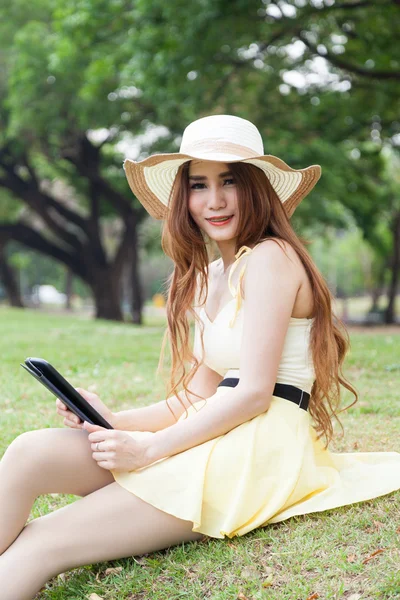 Frau sitzt auf Gras und benutzt ein Tablet. — Stockfoto