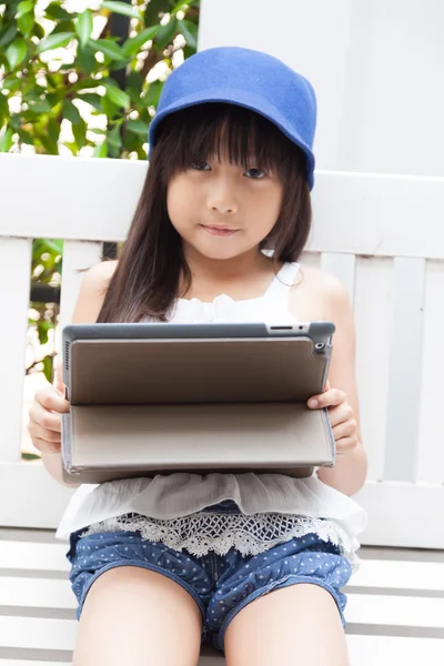 Menina brincando com tablet no banco . — Fotografia de Stock