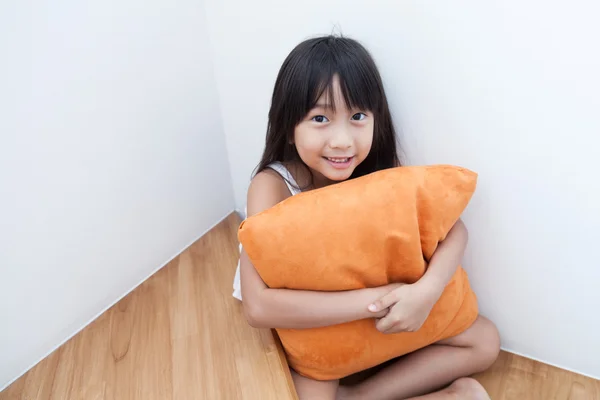 Dziewczyna siedzący tulenie poduszki pomarańczowy. — Zdjęcie stockowe