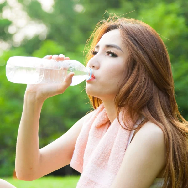 Mujer sentada cansada y bebiendo agua después del ejercicio . —  Fotos de Stock