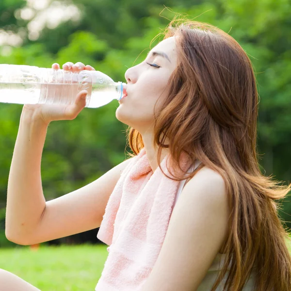 Mujer sentada cansada y bebiendo agua después del ejercicio . —  Fotos de Stock