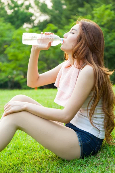 Femme assise fatiguée et buvant de l'eau après l'exercice . — Photo